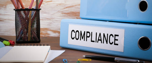 Compliance, Office Binder on Wooden Desk. On the table colored pencils, pen, notebook paper